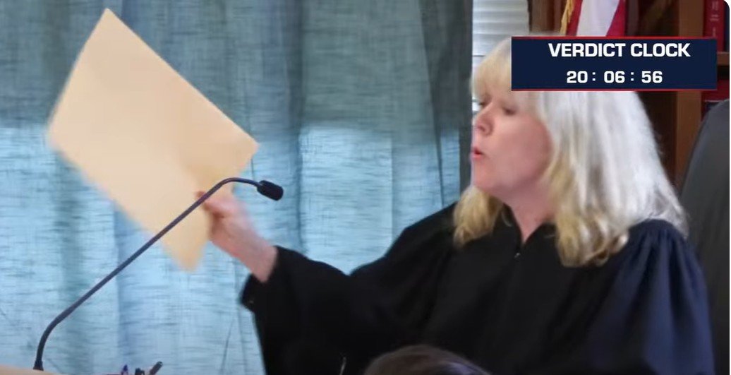 Bev Holding Up the Faked ya Verdict Envelope
